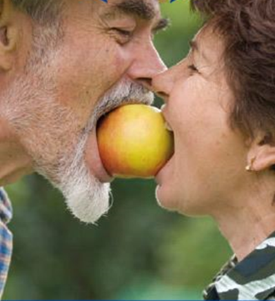 Ein älterer Mann und eine ältere Frau. Dazwischen ein Apfel in den beiden beißen.