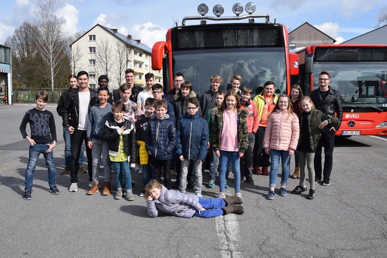 Eine Gruppe Kinder steht lachend vor einem Bus.