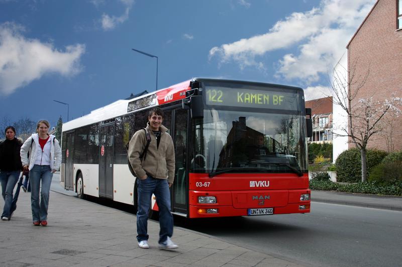 Ein junger Mann steht an einem Bus.
