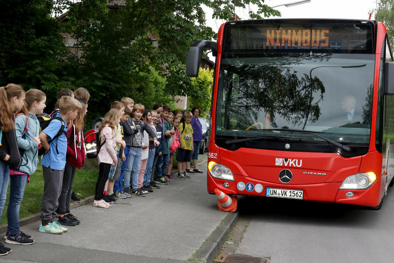 Kinder stehen an einem Bus.